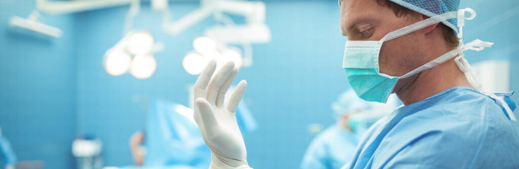 Male surgeon wearing surgical gloves in operation theater