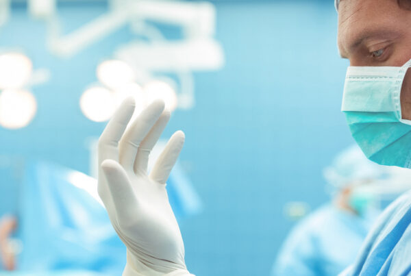 Male surgeon wearing surgical gloves in operation theater