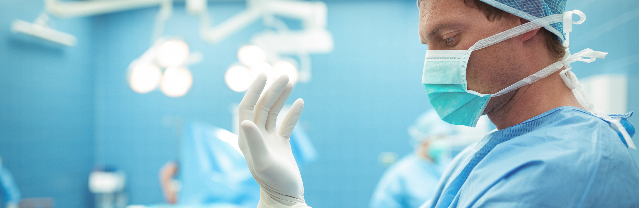 Male surgeon wearing surgical gloves in operation theater